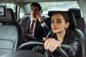 A female taxi driver holds a steering wheel while a businessman talks on smartphone after calling for taxis East Peoria IL