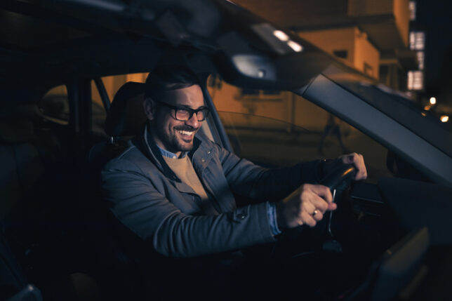 Taxis Pekin IL, Happy charming man driving his modern car at night